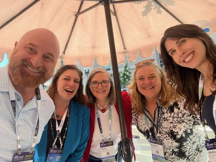 Chris Gloede with four association professionals under a patio umbrella at ASAE MMC+Tech.