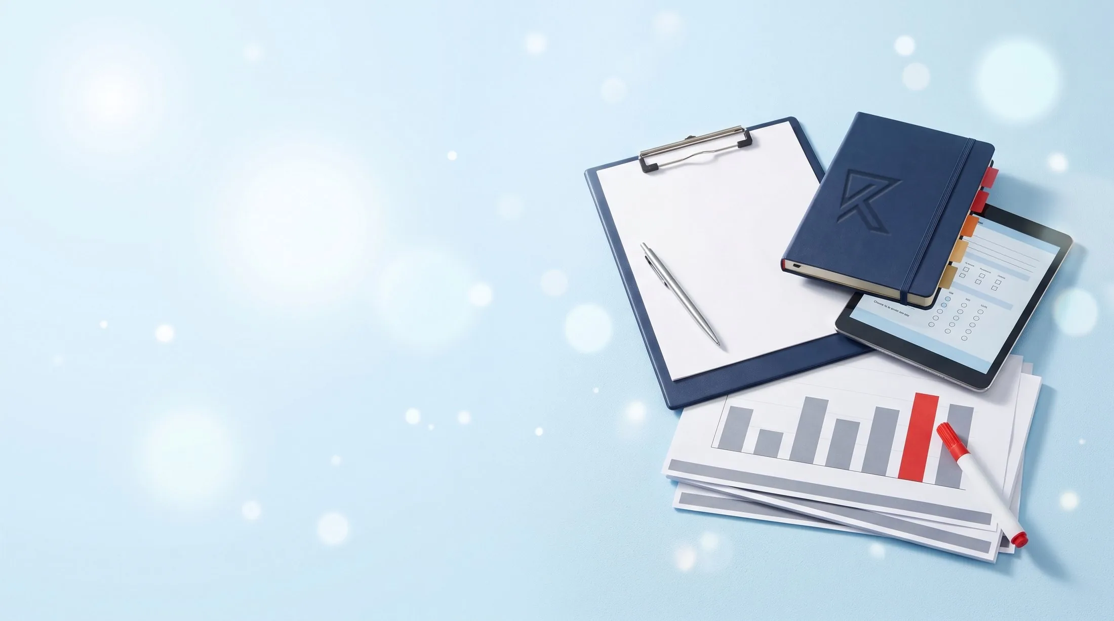 A pile of a clipboard, a tabbed navy notebook with the Ricochet mark pressed into its cover, a tablet showing an online survey and presentation pages with a bar chart.