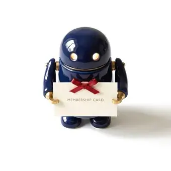 A small navy robot holding a membership card tied with a ribbon.